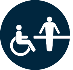 person in a wheelchair and a person standing behind a table 