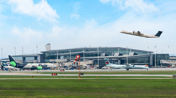 photo of the terminal, grass in the forefront, aircraft in the sky having just taken off